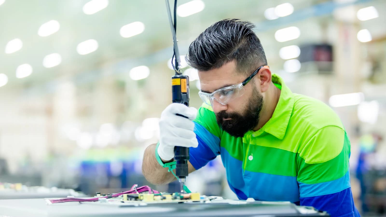 A technician working on a circuit board with precision tools